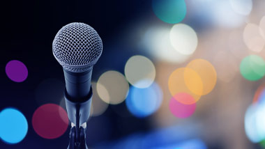 looking out past a microphone at blurred colored lights