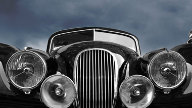 old model black car with dark sky behind it