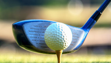 golfer lining up ball and club